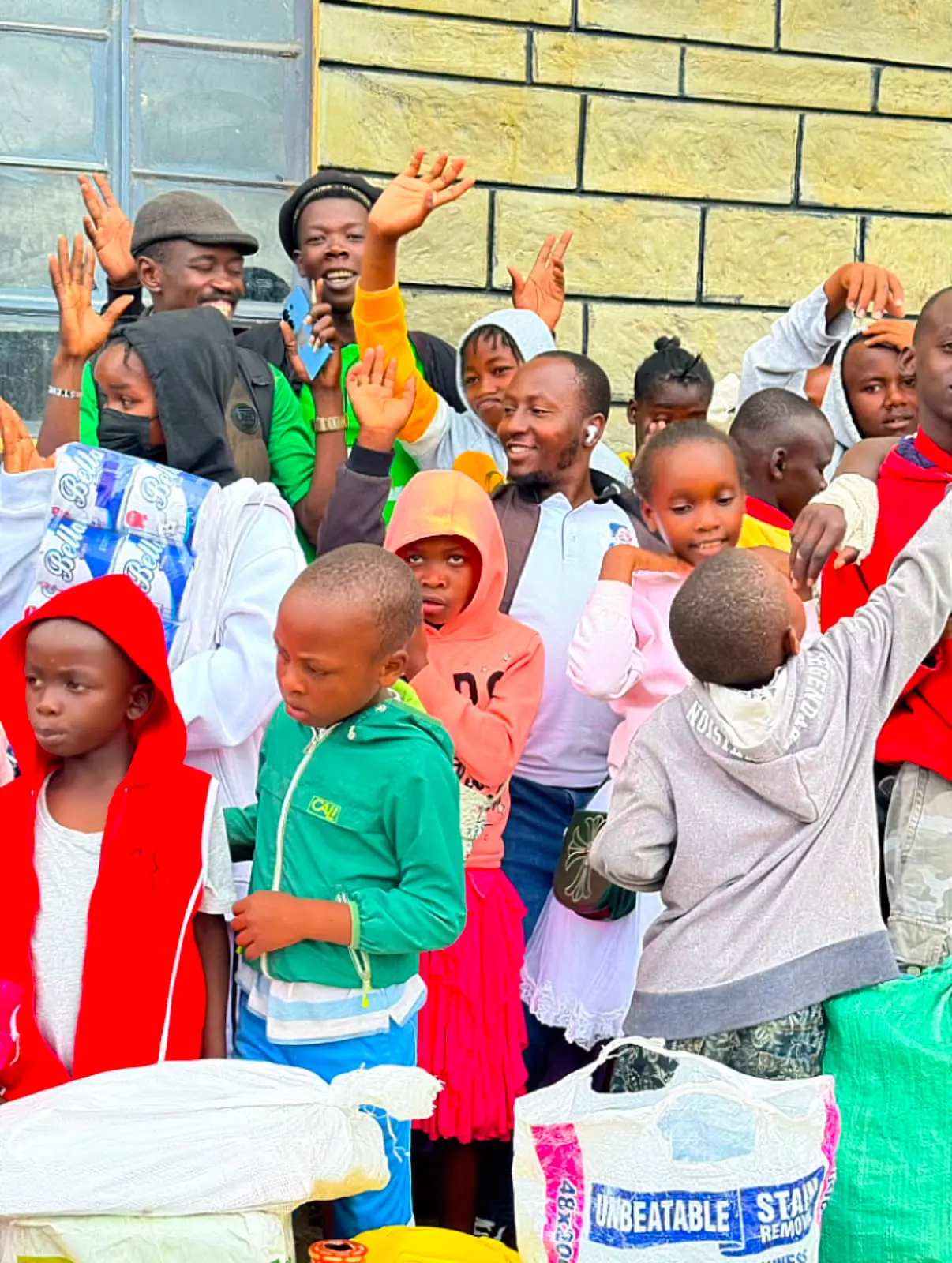 Children waving and cheering at a Nyasuba Golden Pillars community event